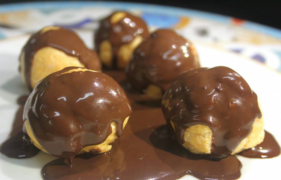 Profiteroles filled with white cream and covered with chocolate at Restaurante Raices